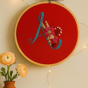 Handmade embroidery design featuring letter A initial with floral patterns on a round hoop
